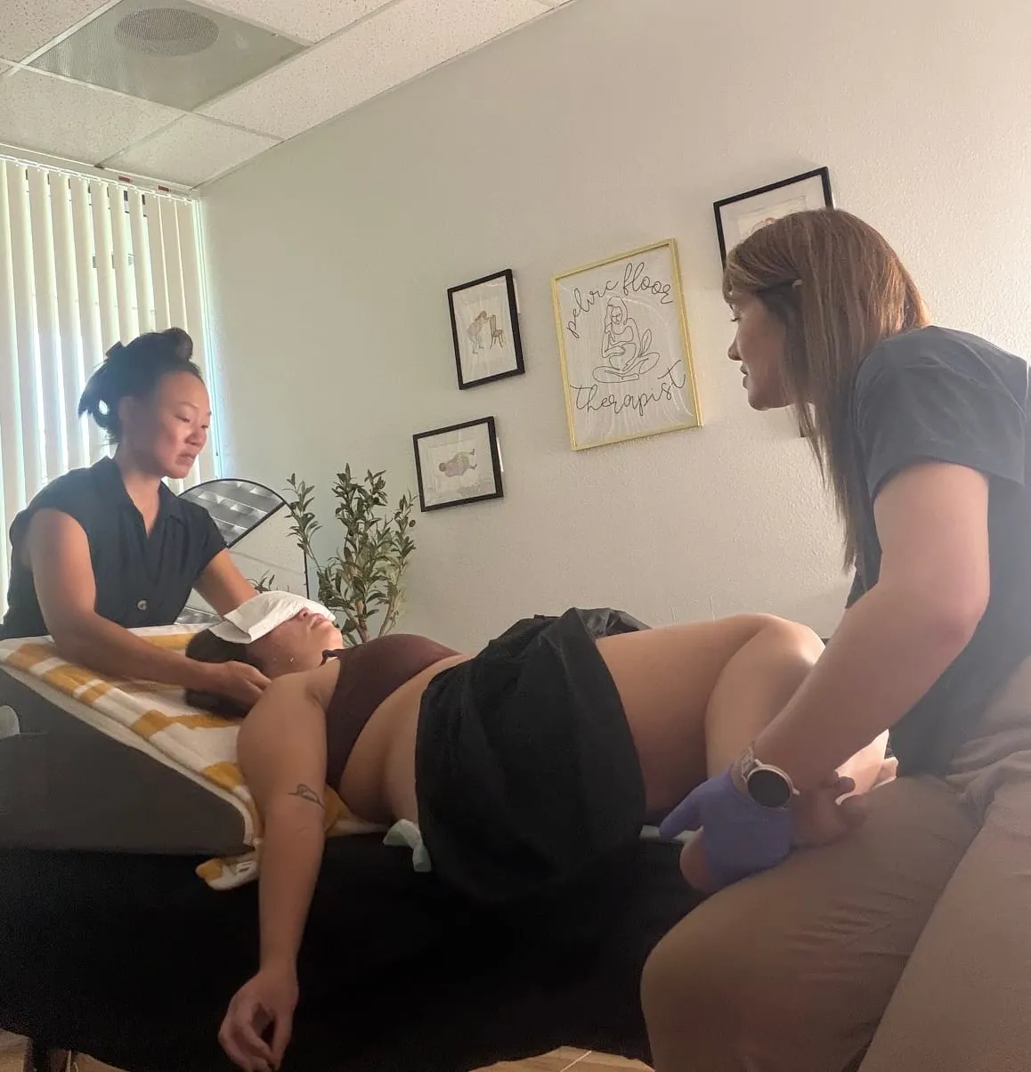 Nina Jung, L.Ac. performs jaw work at the patient's head while Ashlee Gendron, PT supports the lower body during a Reconnection Session at the AG Physical Therapy clinic.